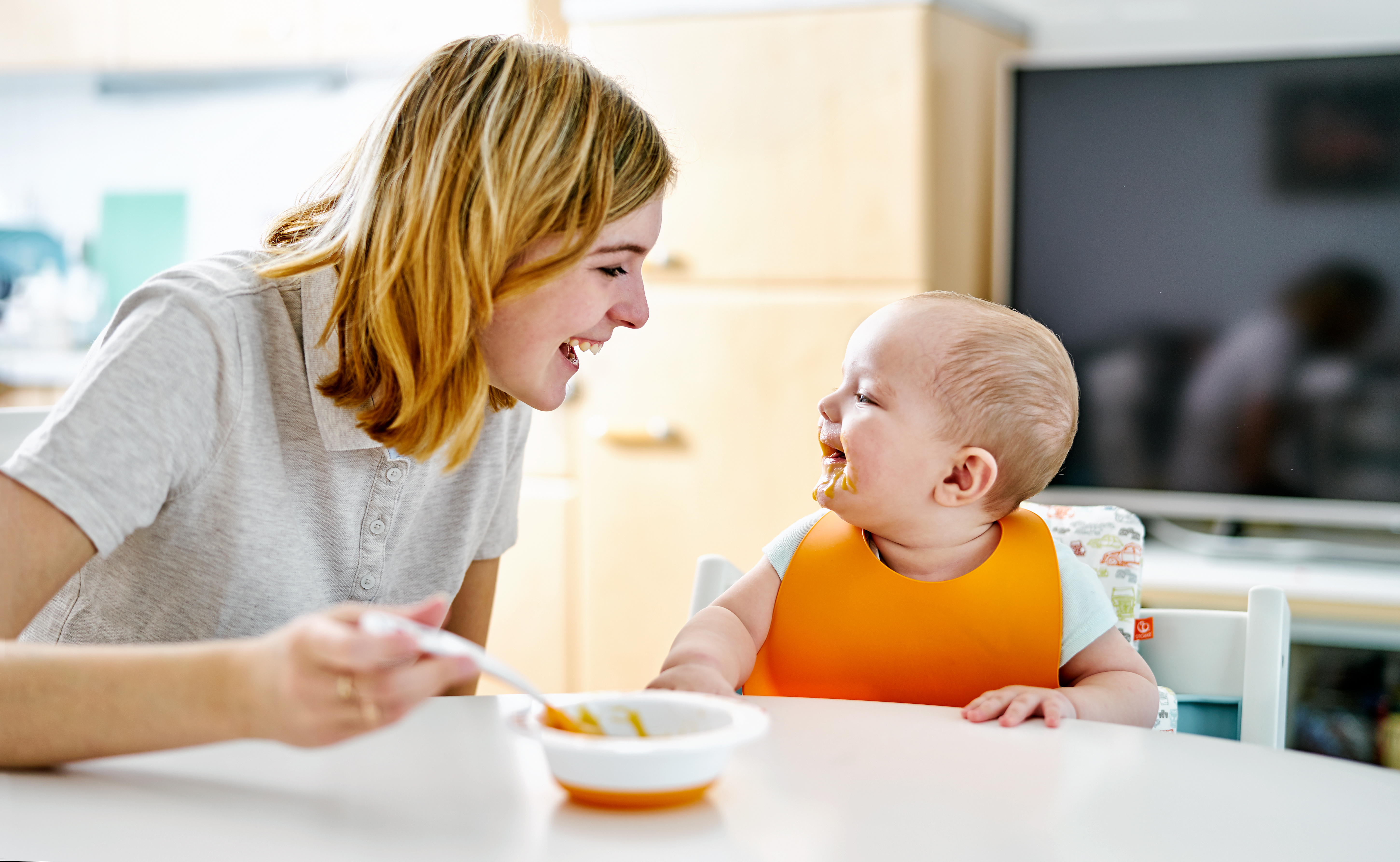 baby eating food with mother